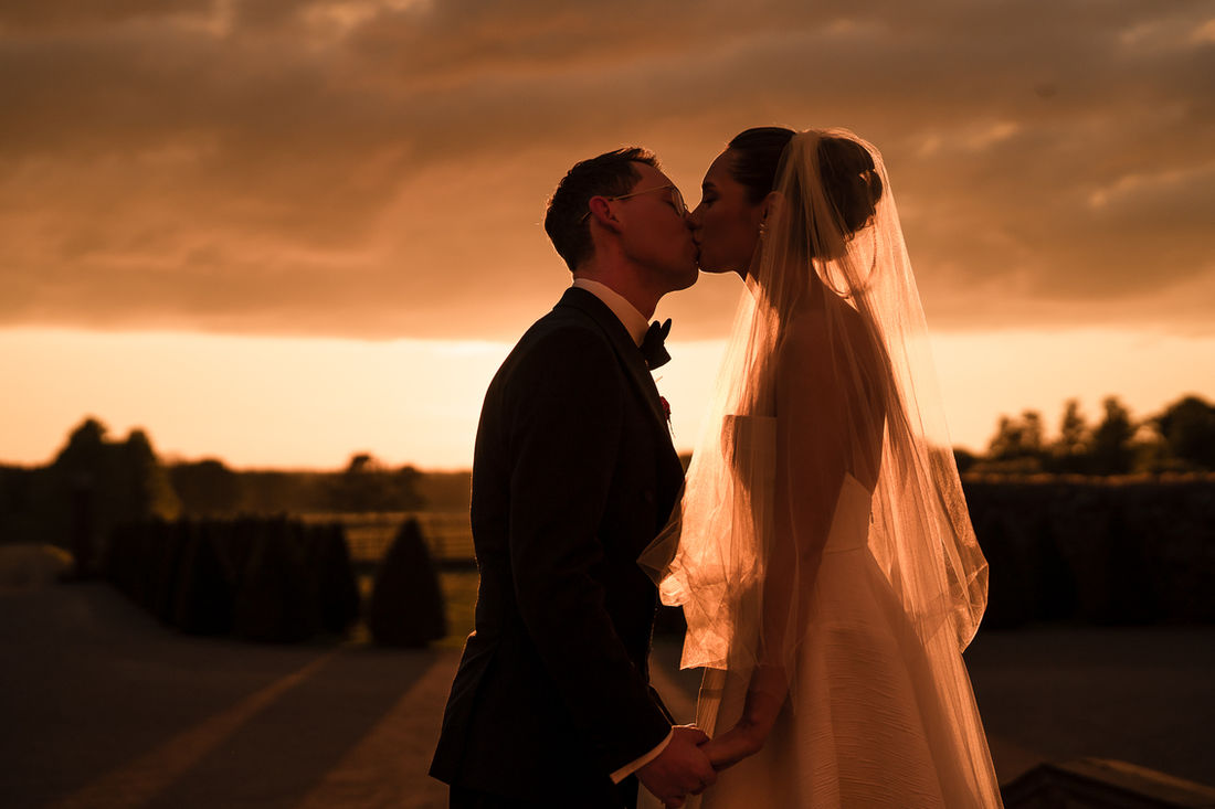 Couple kissing beneath a golden sunset sky