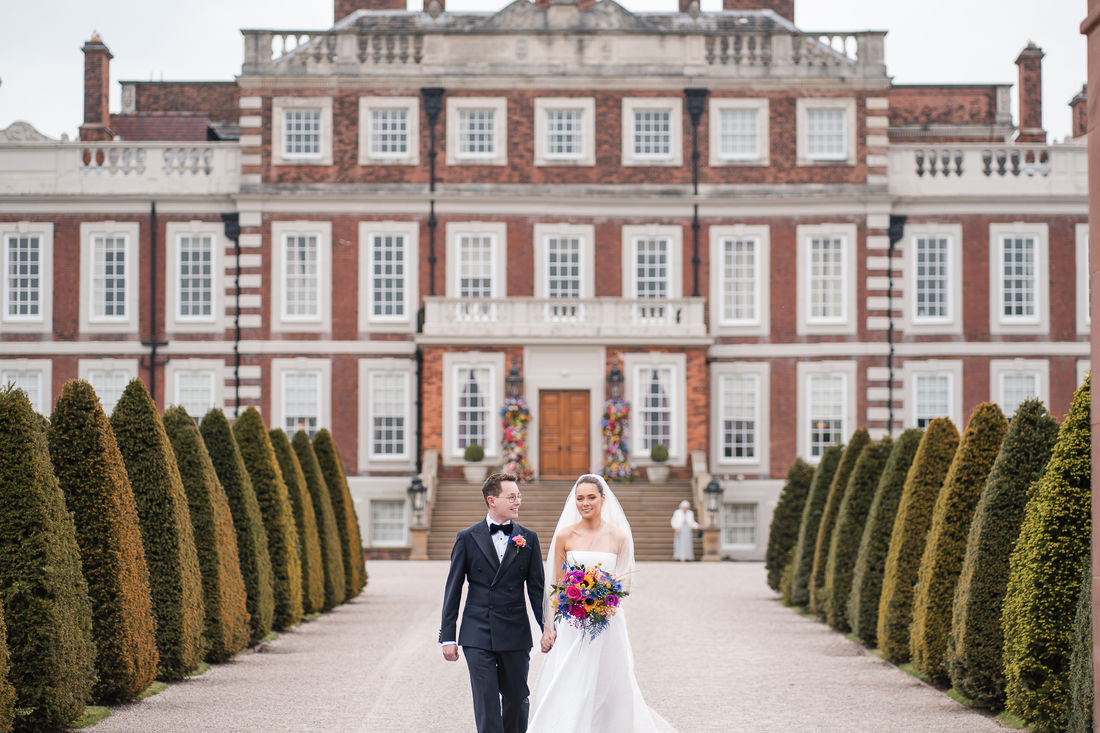 Couple standing before the facade of a grand country house