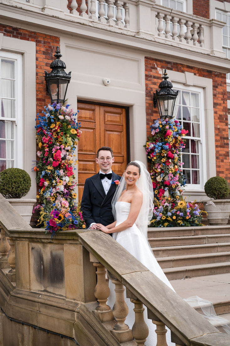 Newlyweds at the top of grand stone steps lined with florals
