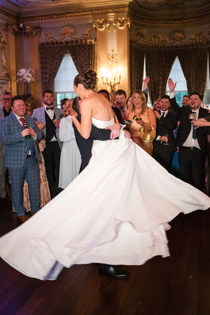 First dance surrounded by guests in a candlelit ballroom